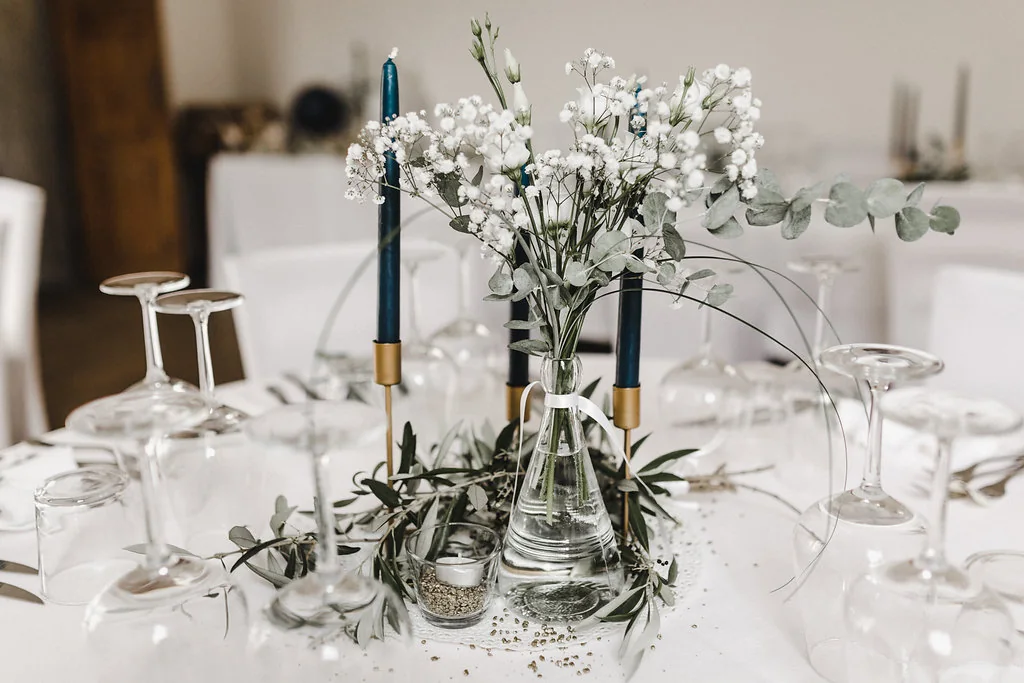 Hochzeitstisch mit Eukalyptus, Schleierkraut und dunkelblauen Kerzen